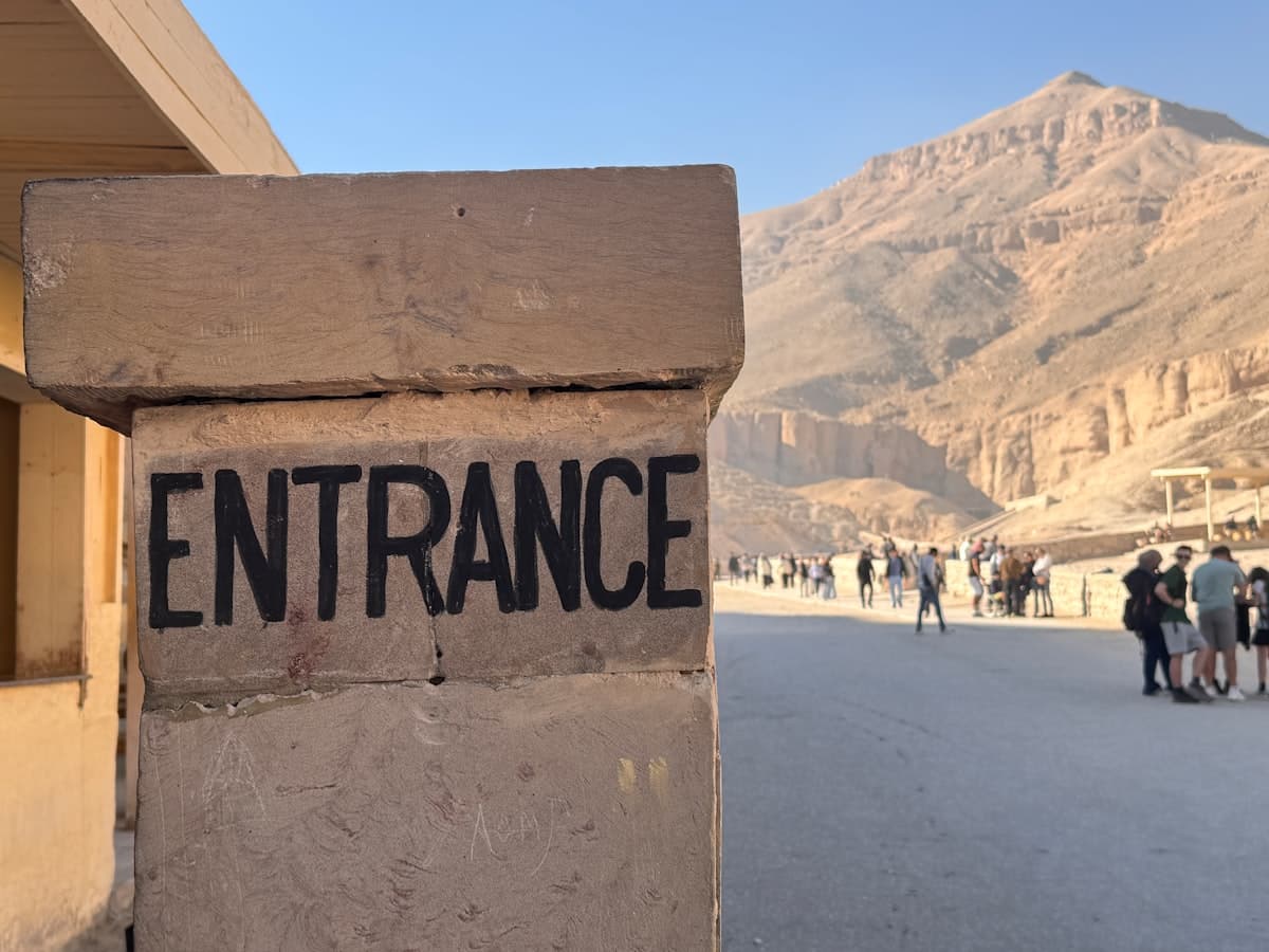 Entrance sign with people and mountains in background