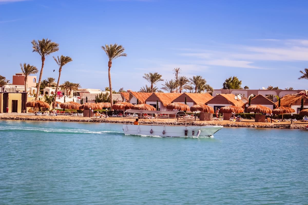 A boat traveling down a river next to a beach