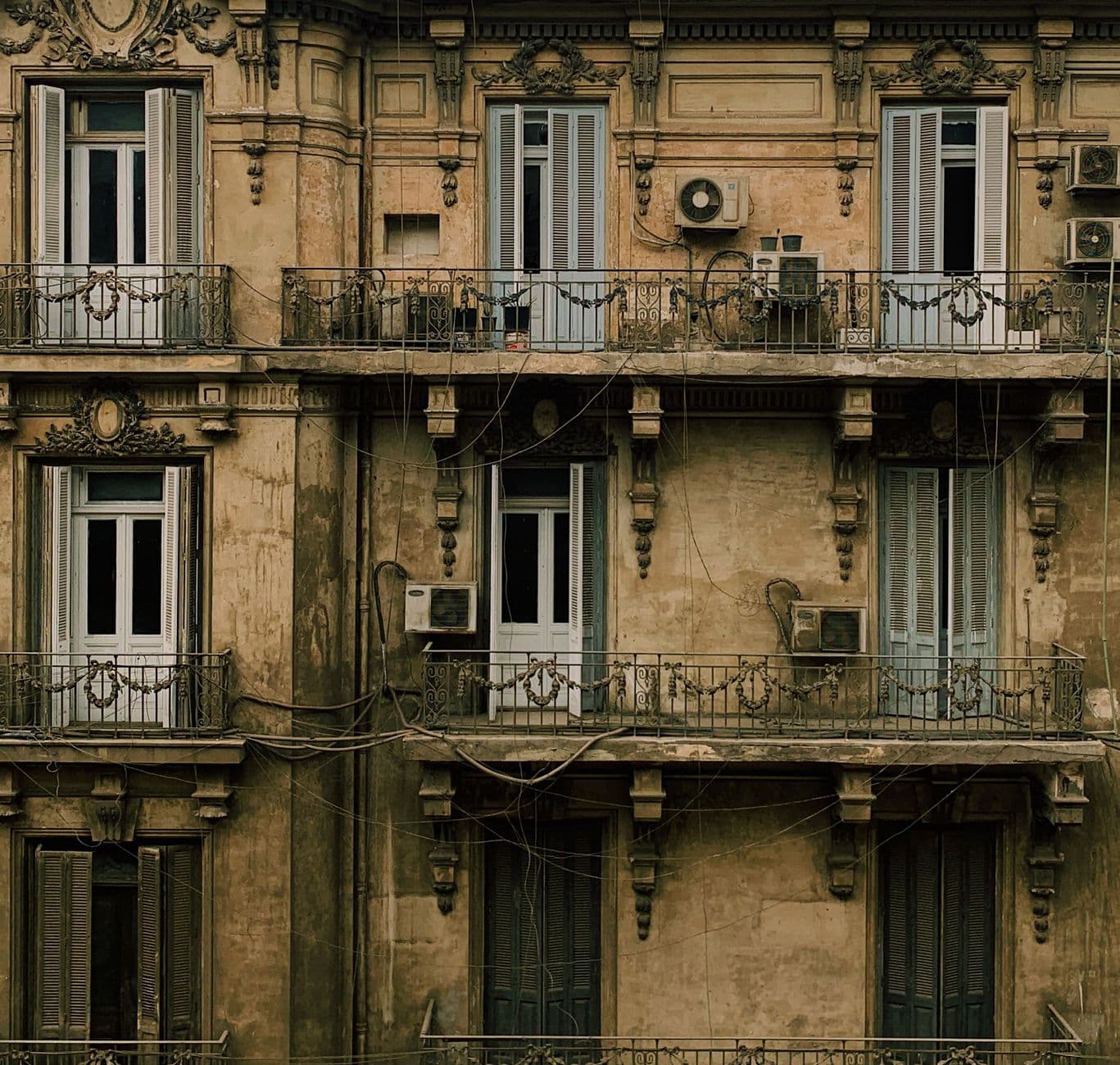 Backdrop of aged house exterior with fenced balconies and doors in town in daylight