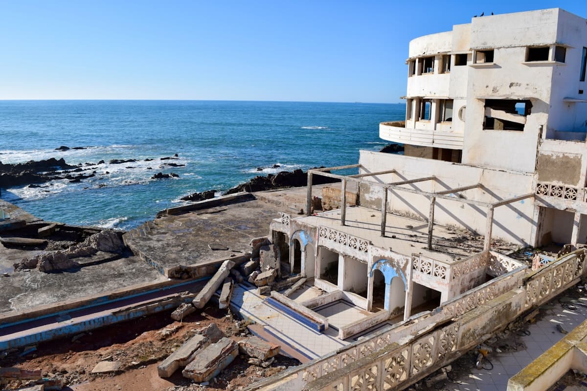Abandoned building ruins by the sea under a clear sky.