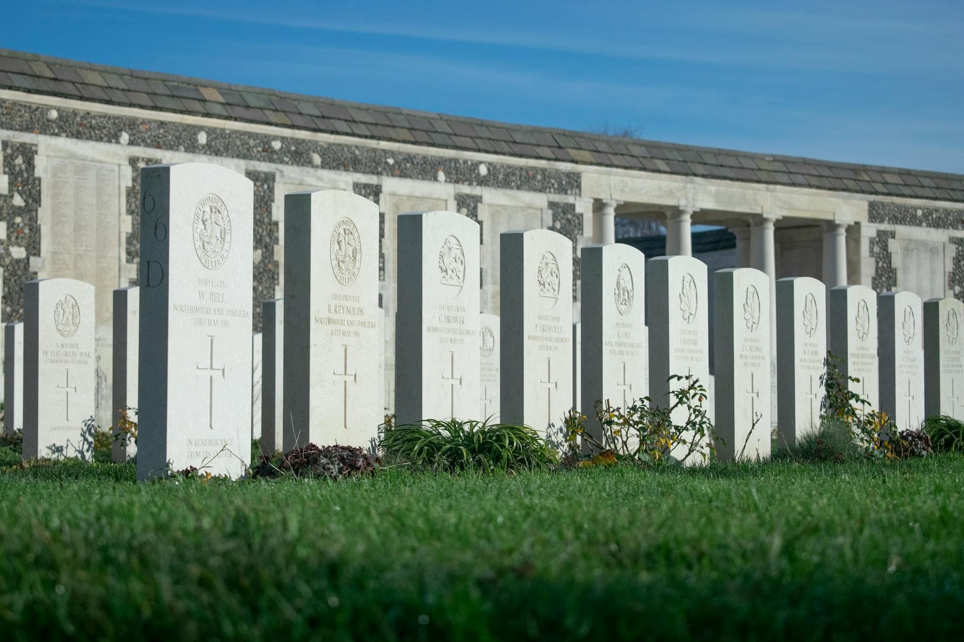 Aligned headstones in a World War II cemetery on a sunny day.