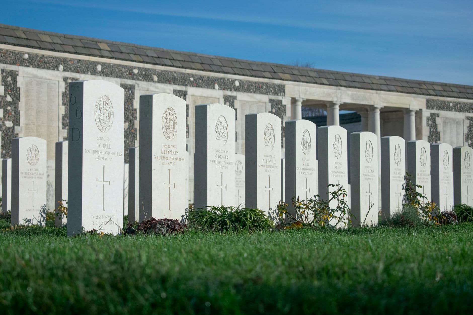 Aligned headstones in a World War II cemetery on a sunny day.