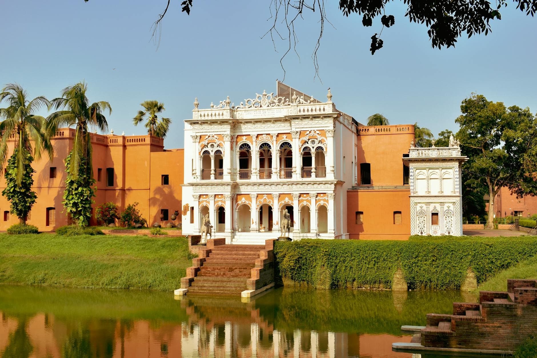 A stunning historic mansion with intricate details beside a serene lake, set in lush gardens.