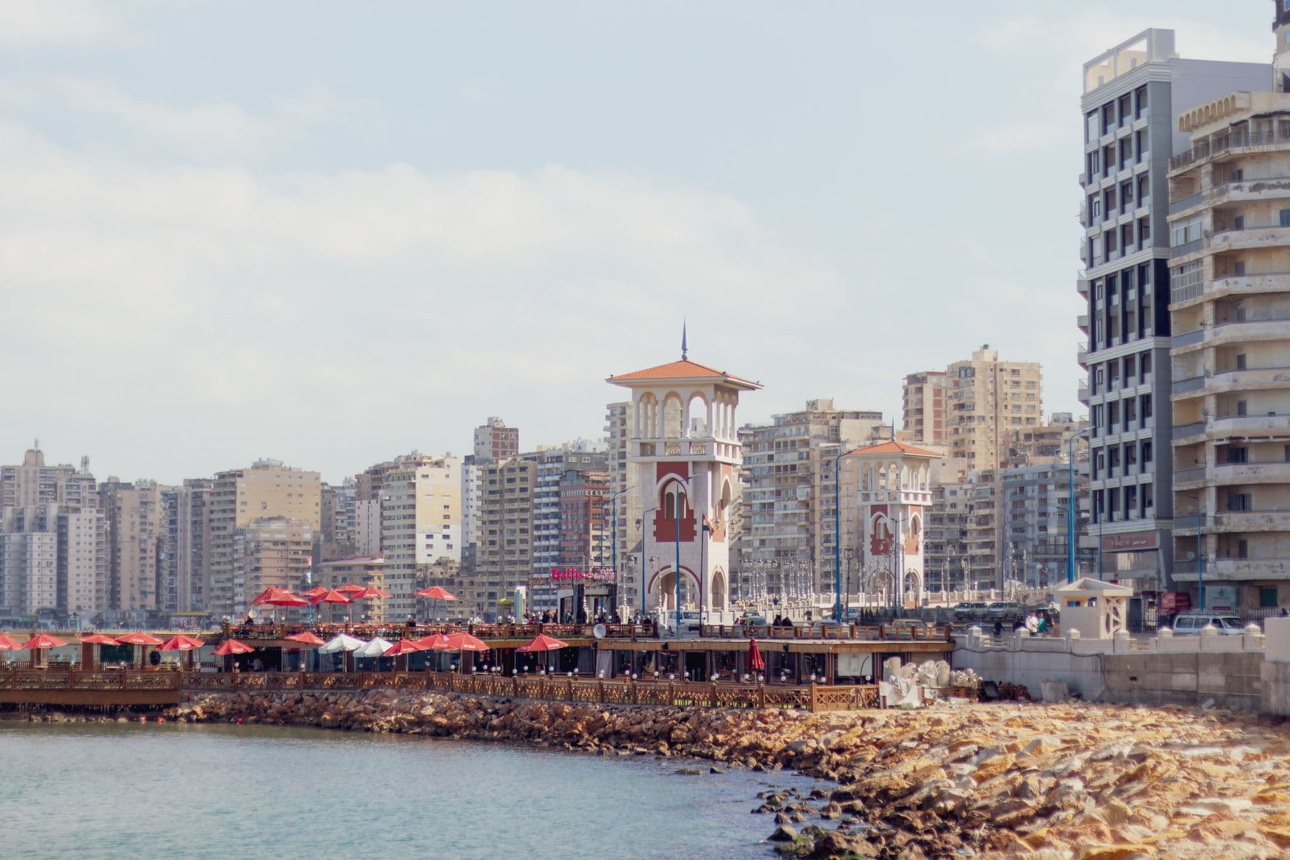 A coastal view of Alexandria's promenade featuring iconic architecture and a vibrant cityscape.