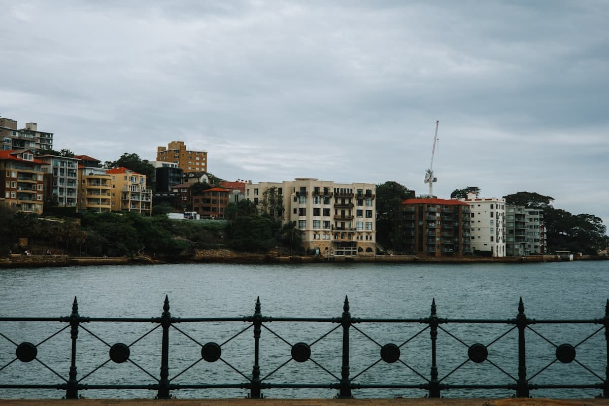 Apartment buildings line a waterfront under cloudy skies.