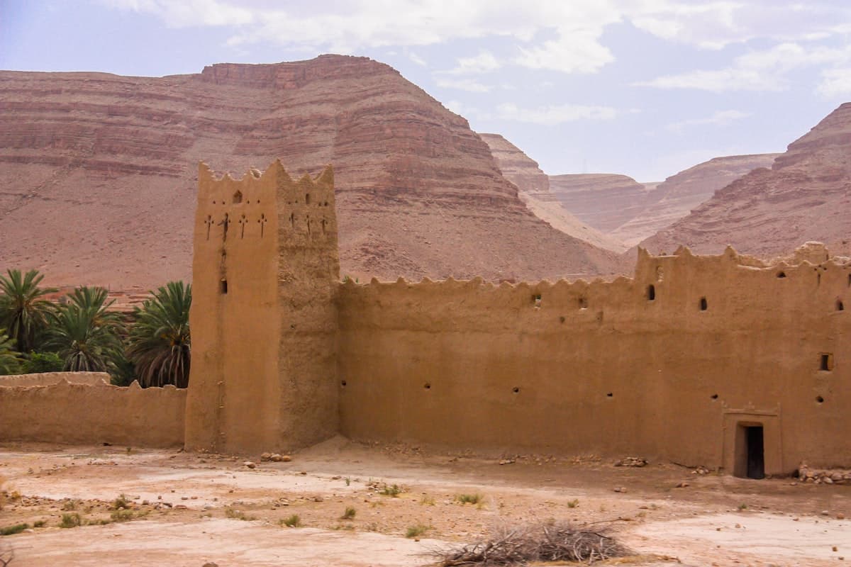 an adobe building in the desert with mountains in the background