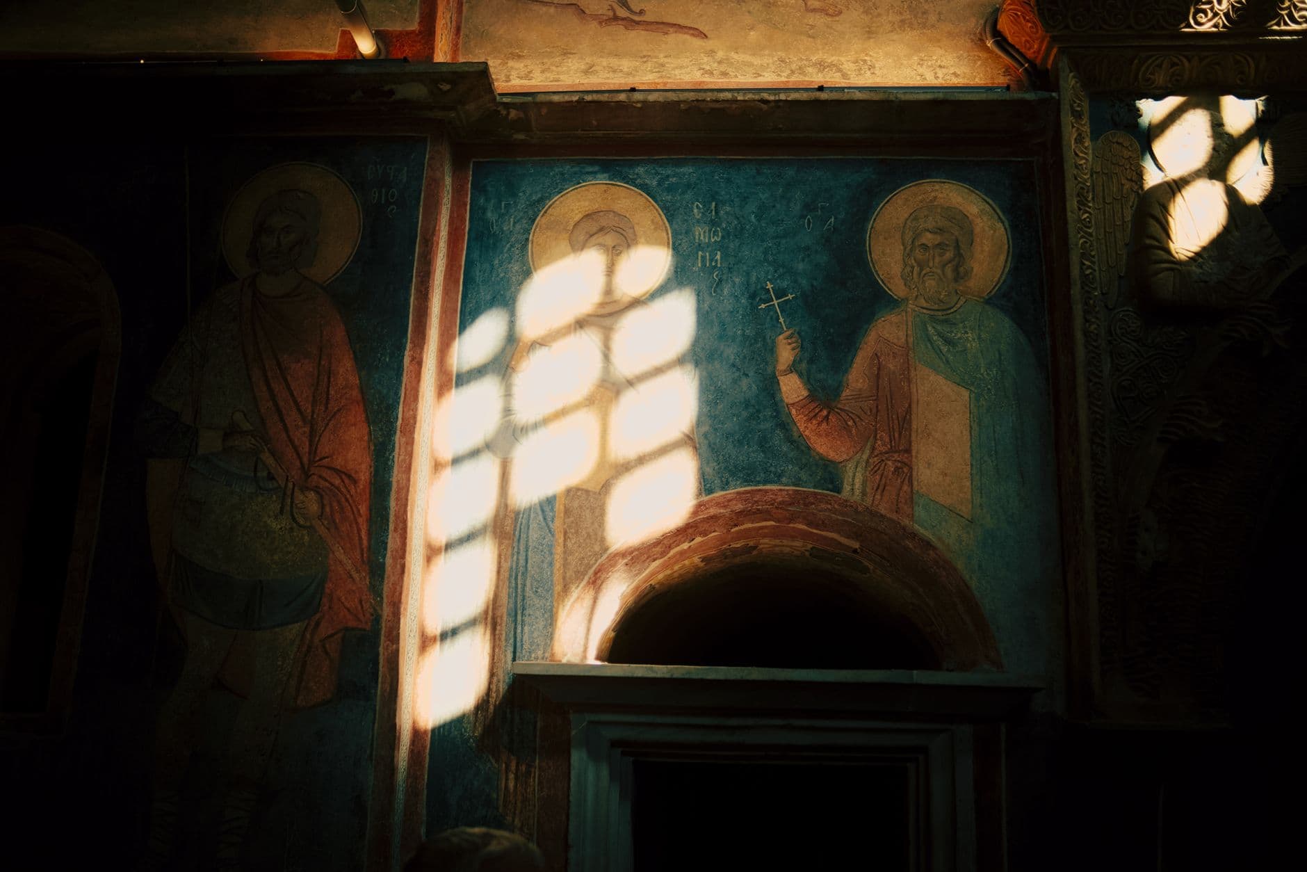 A captivating view of historic church frescoes illuminated by soft, golden light filtering through a window.