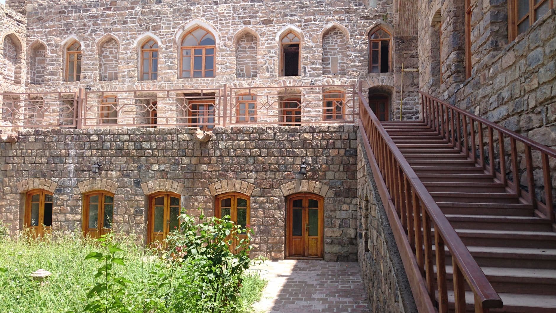 View of a historic stone monastery with arched windows and stairs.