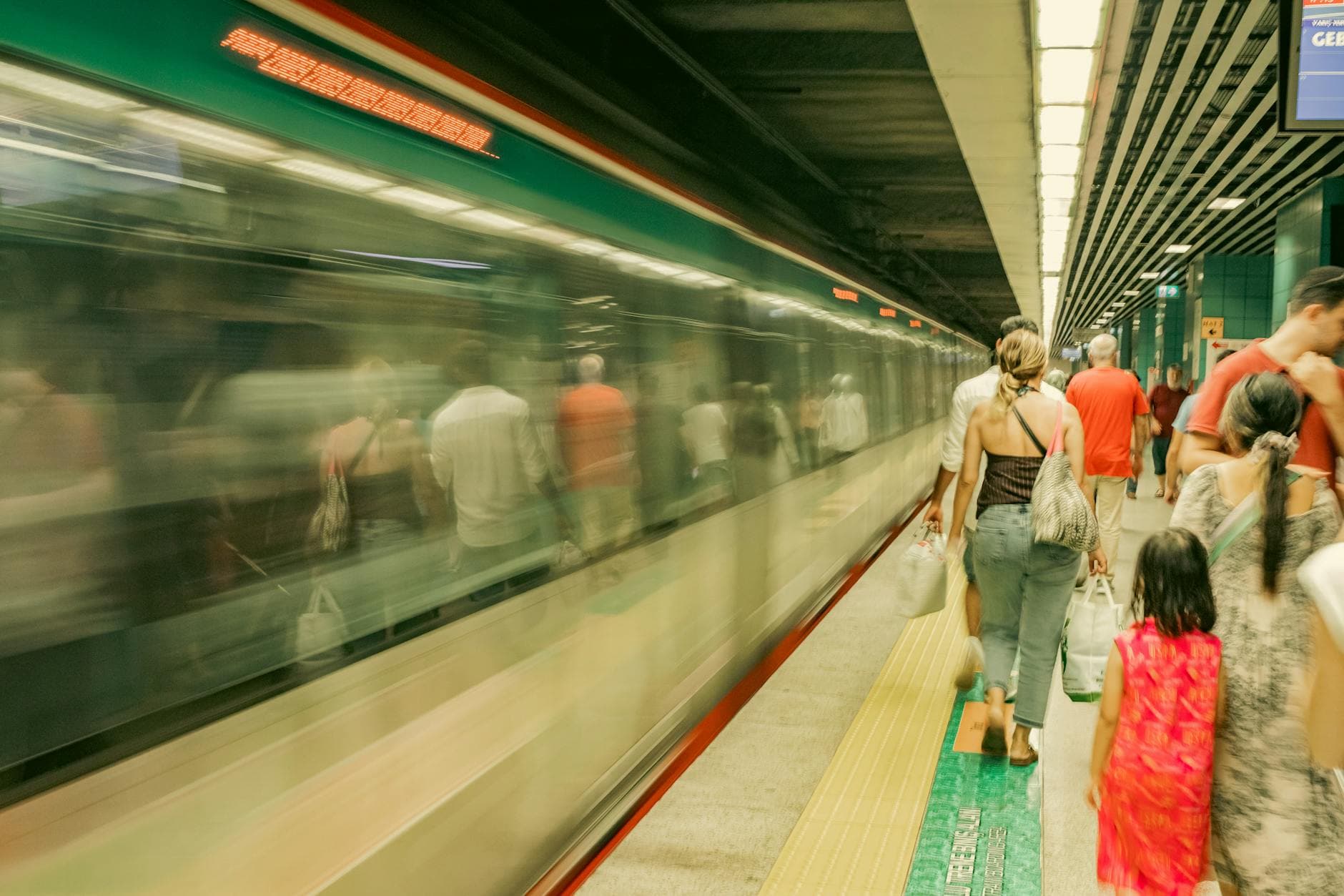 Commuters wait as a subway train passes by, capturing the hustle of urban travel.