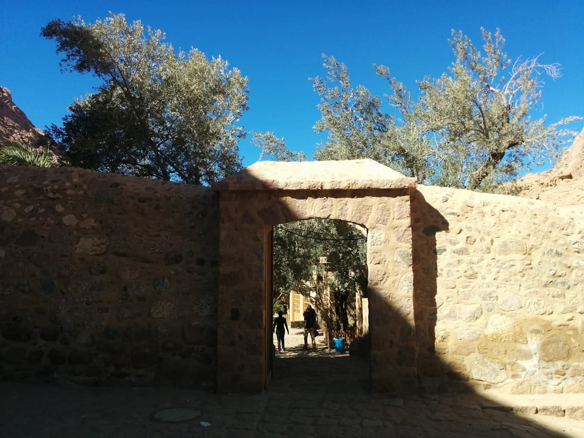 a stone wall with a doorway and people walking through it