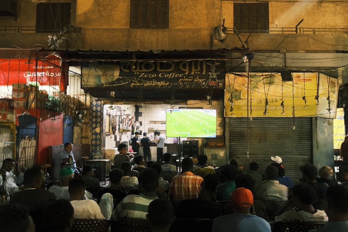 People watching soccer game on outdoor screen at night