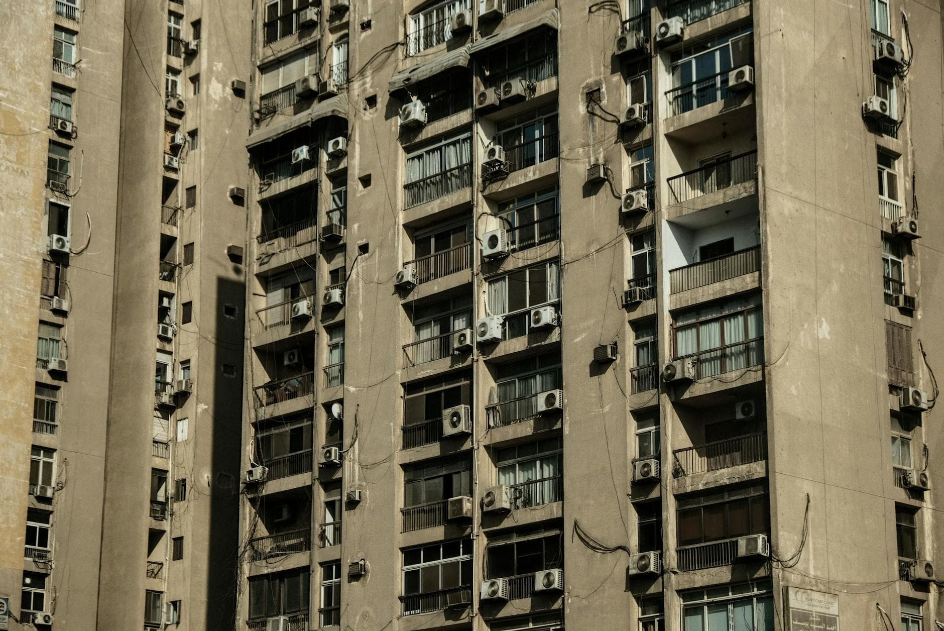 Close-up of a high-rise apartment building in Cairo, Egypt with numerous air conditioners on the facade.
