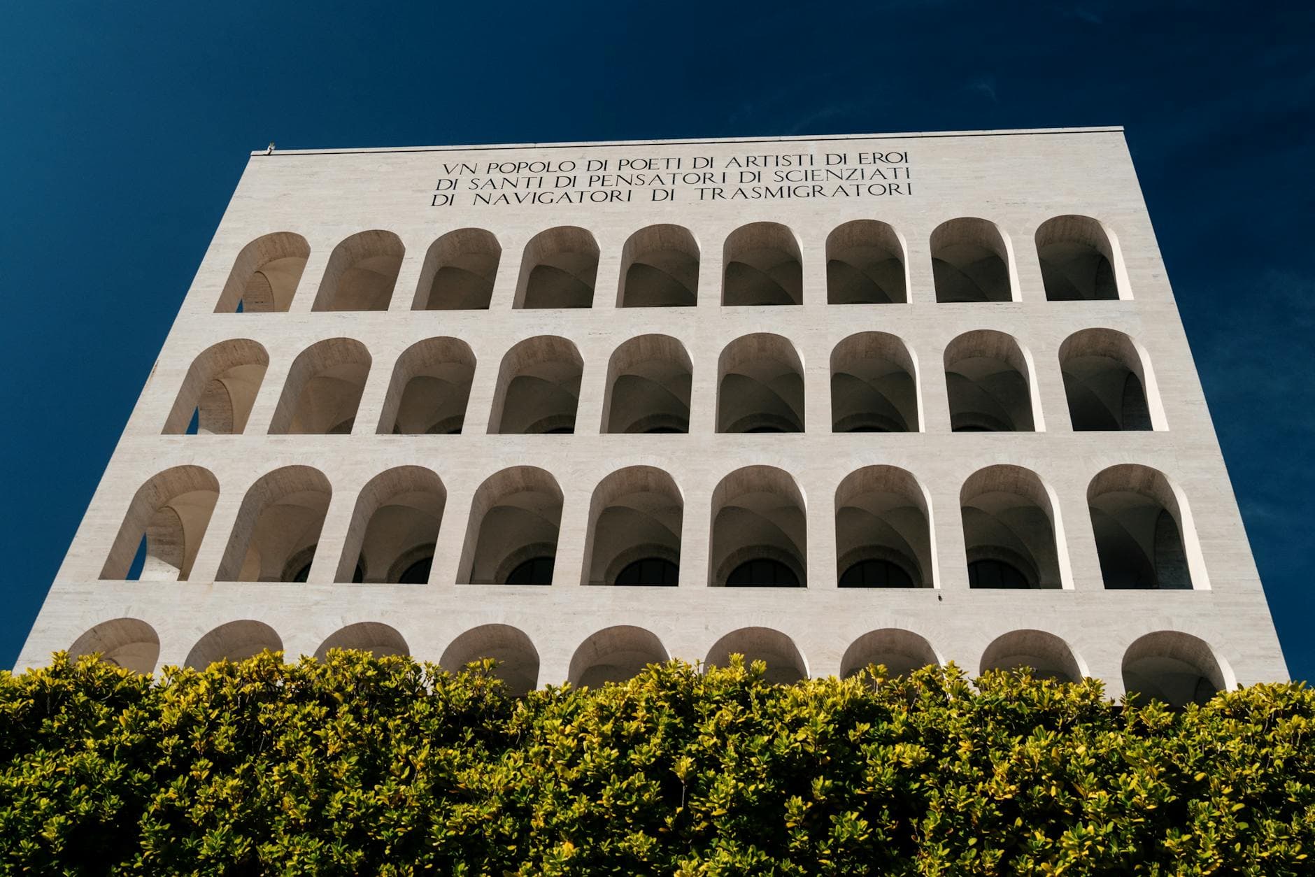 Low angle view of iconic modernist architecture in Rome, showcasing symmetrical arches and clear blue sky.
