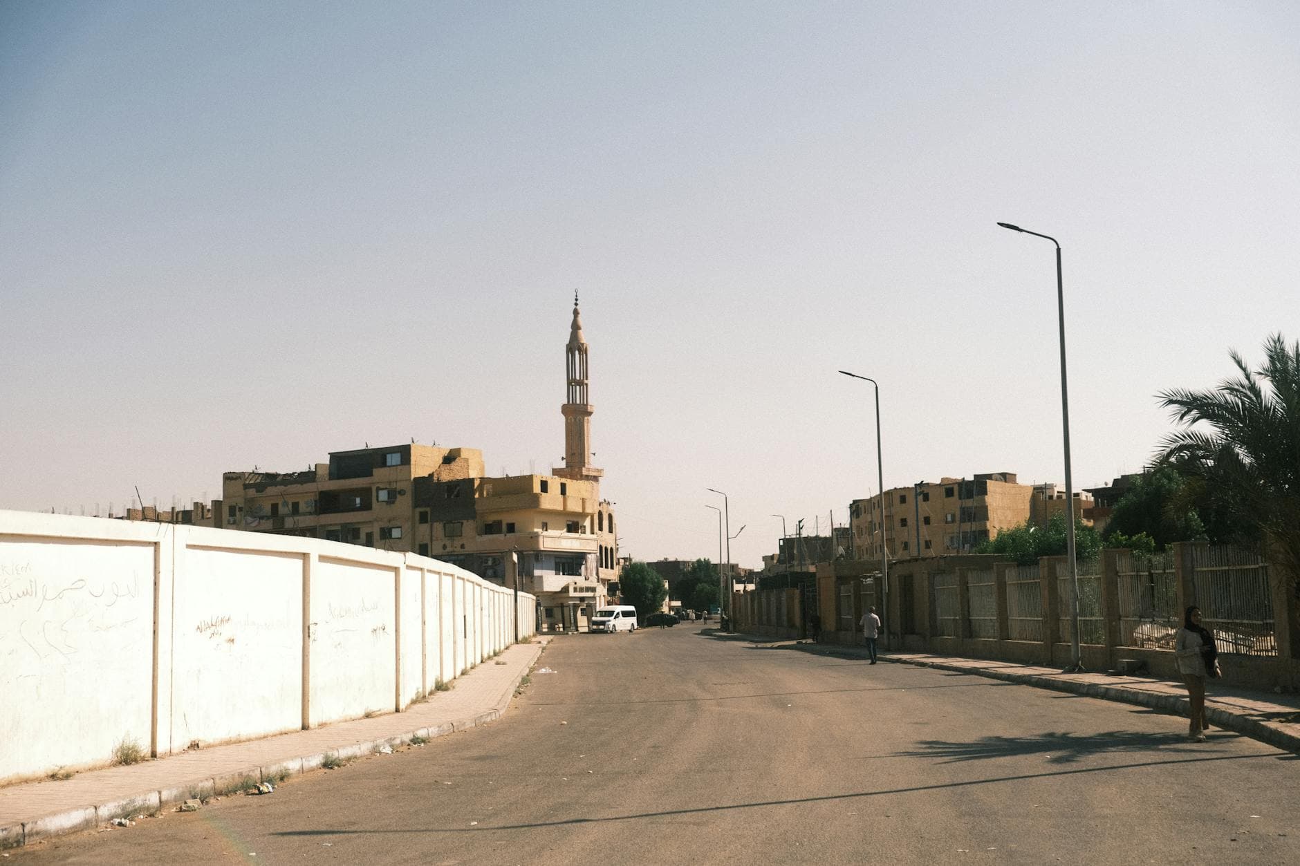 Tranquil street view in Luxor, Egypt featuring a mosque minaret and urban architecture under a clear sky.