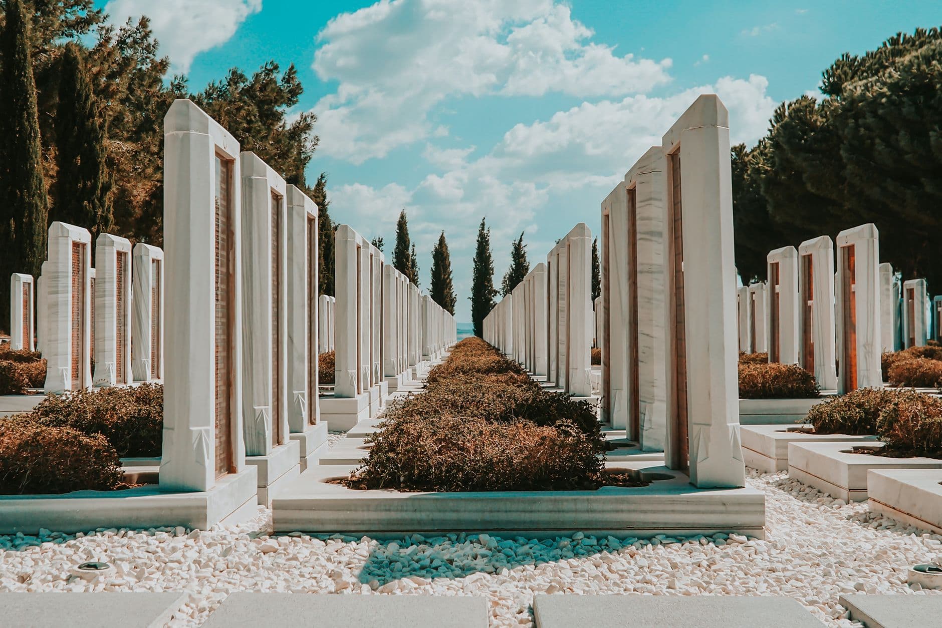 Rows of marble tombstones under a bright sky at Çanakkale Cemetery, capturing a peaceful summer atmosphere.