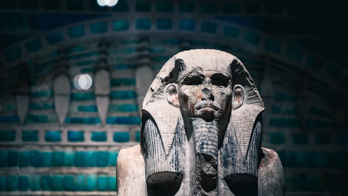 Ancient egyptian pharaoh statue with decorative background.