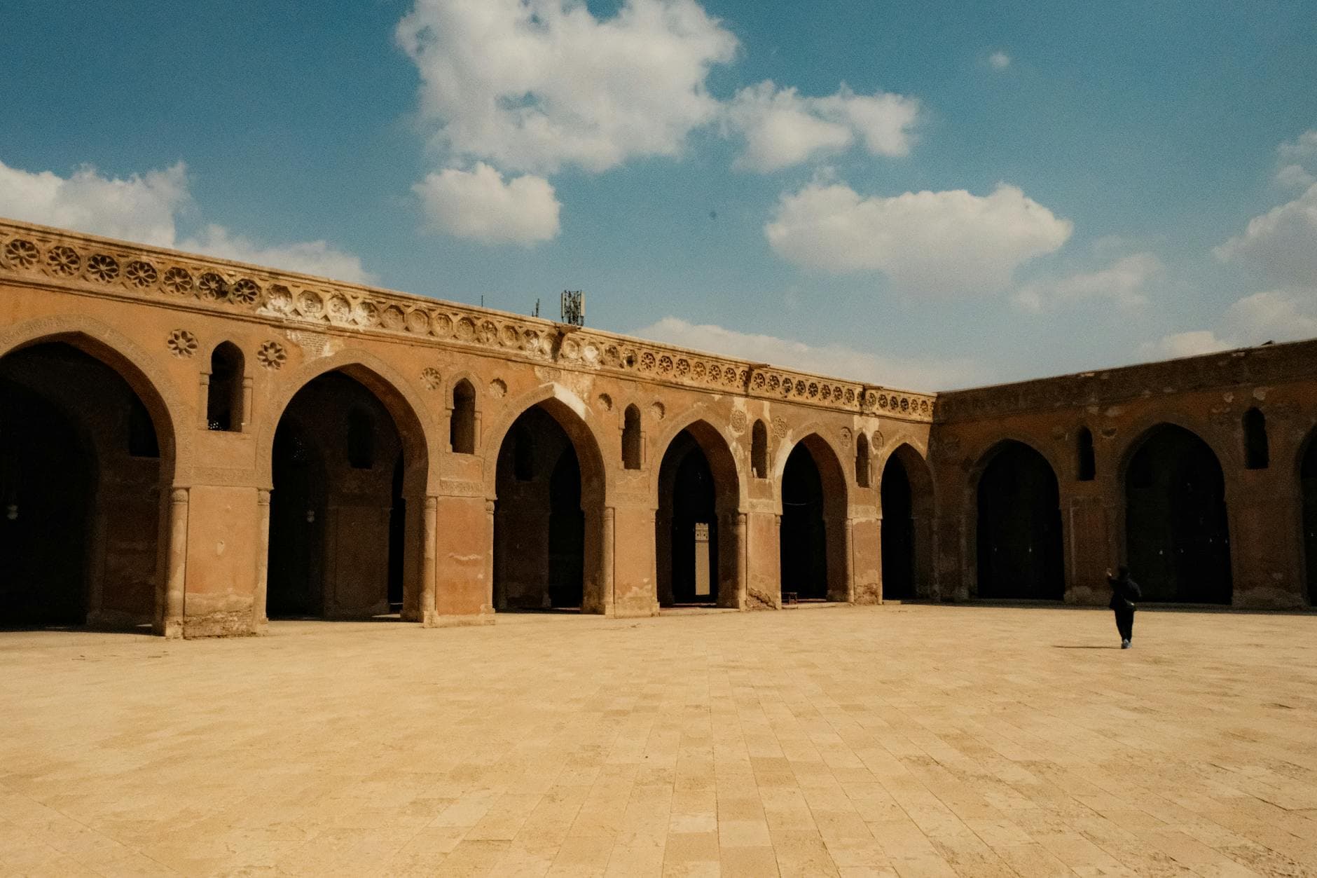 Stunning view of a historical courtyard with arched doorways and clear sky.