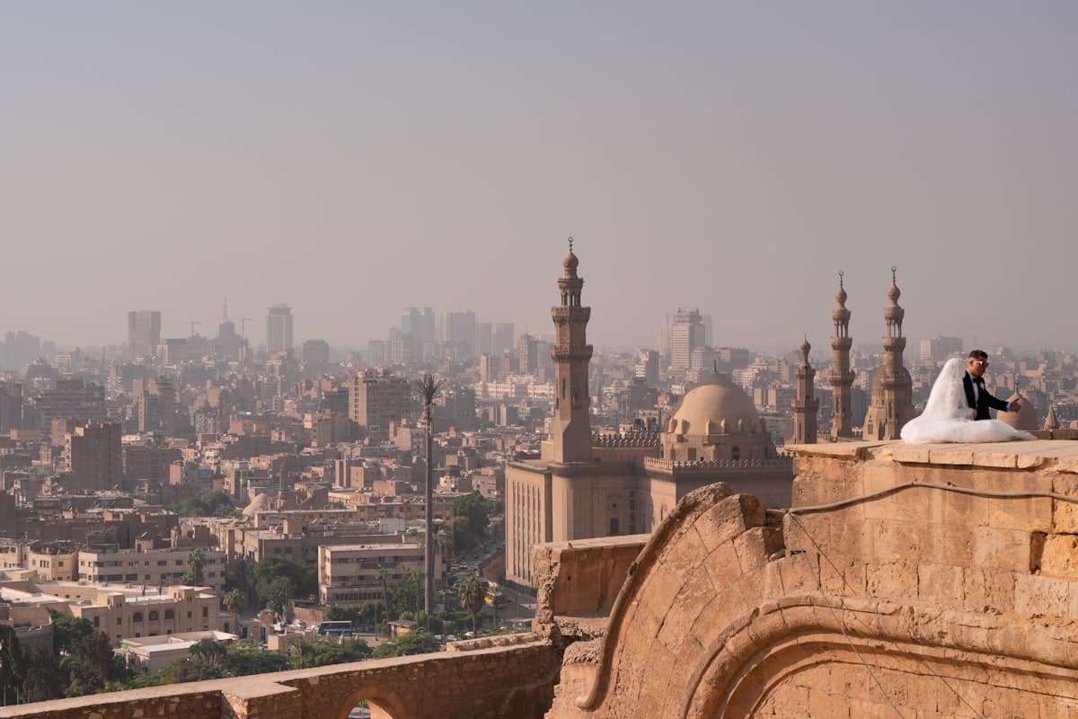 Newlyweds pose on ancient rooftop overlooking cityscape