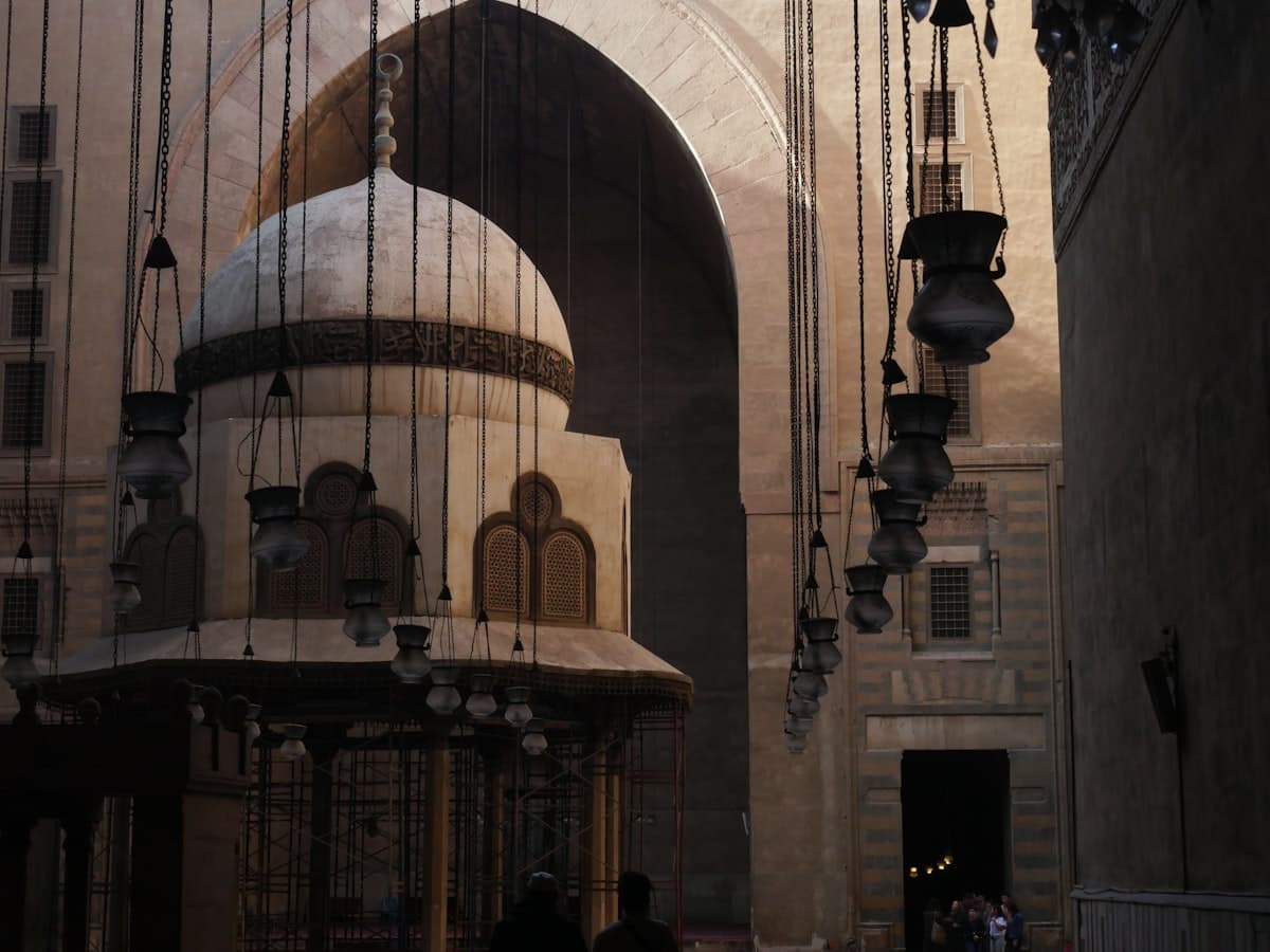 Ornate mosque interior with hanging lanterns and dome
