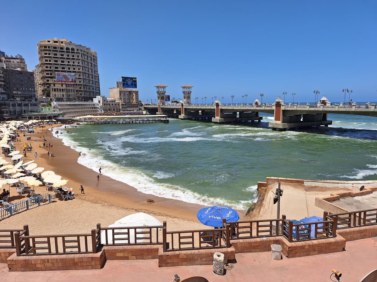 A panoramic view of a beach with a pier in the background
