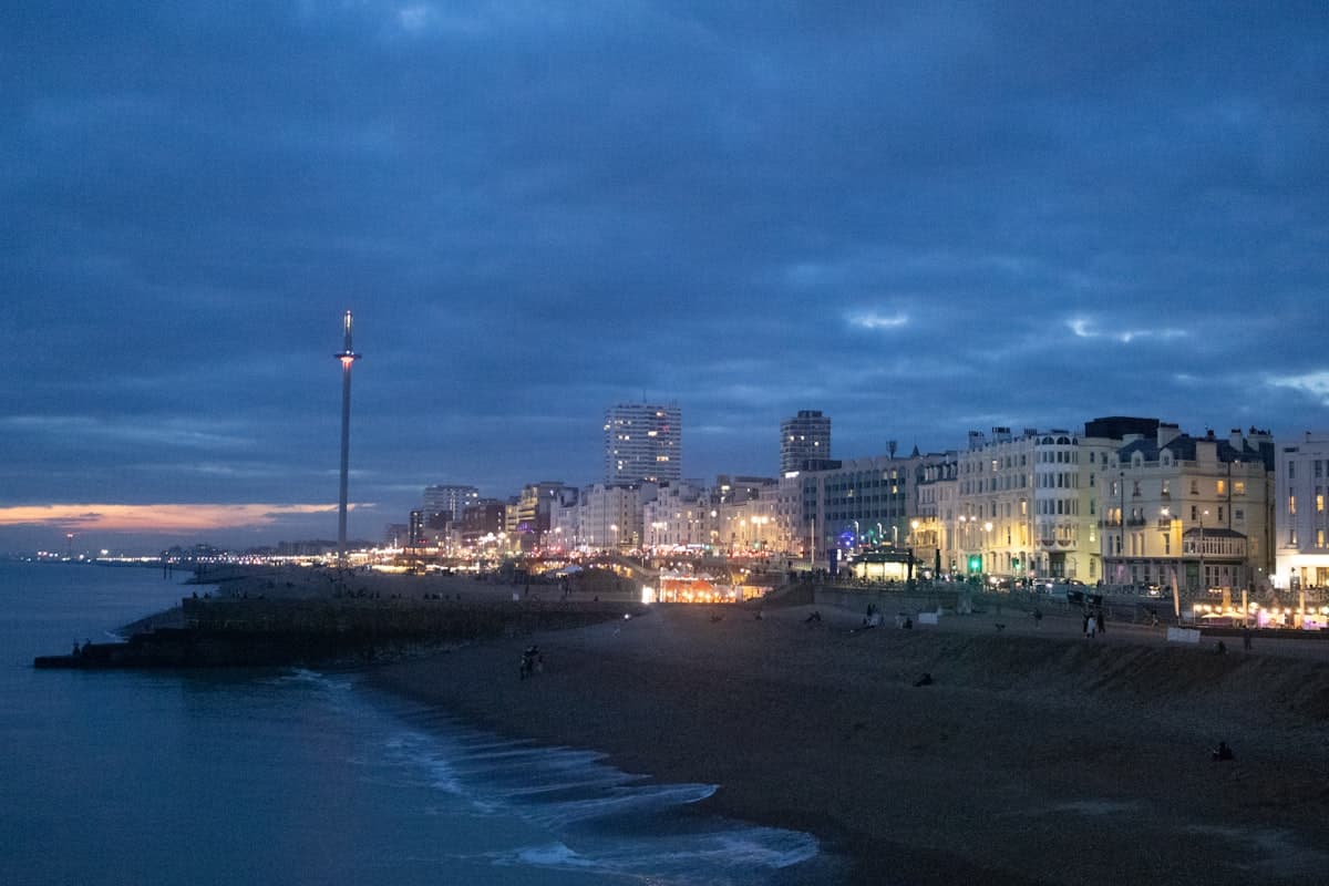 City lights reflect on the ocean at dusk