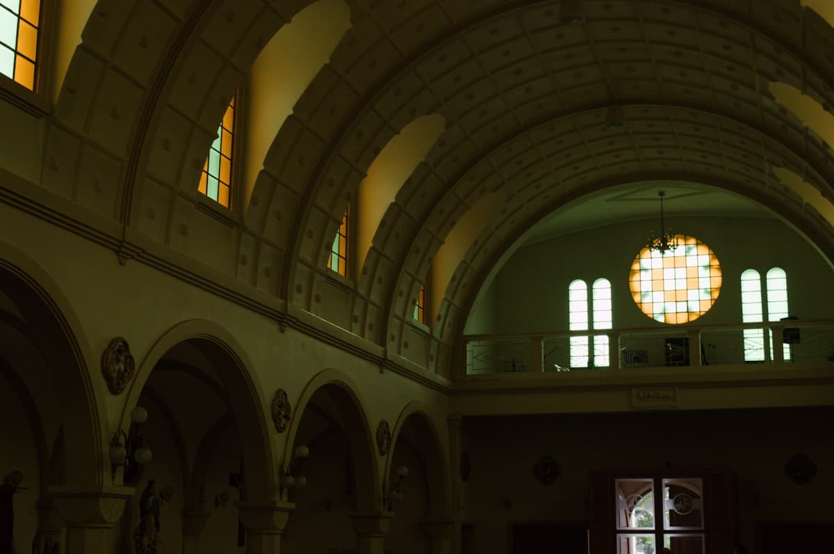 Interior of a church with arched ceilings and stained glass.