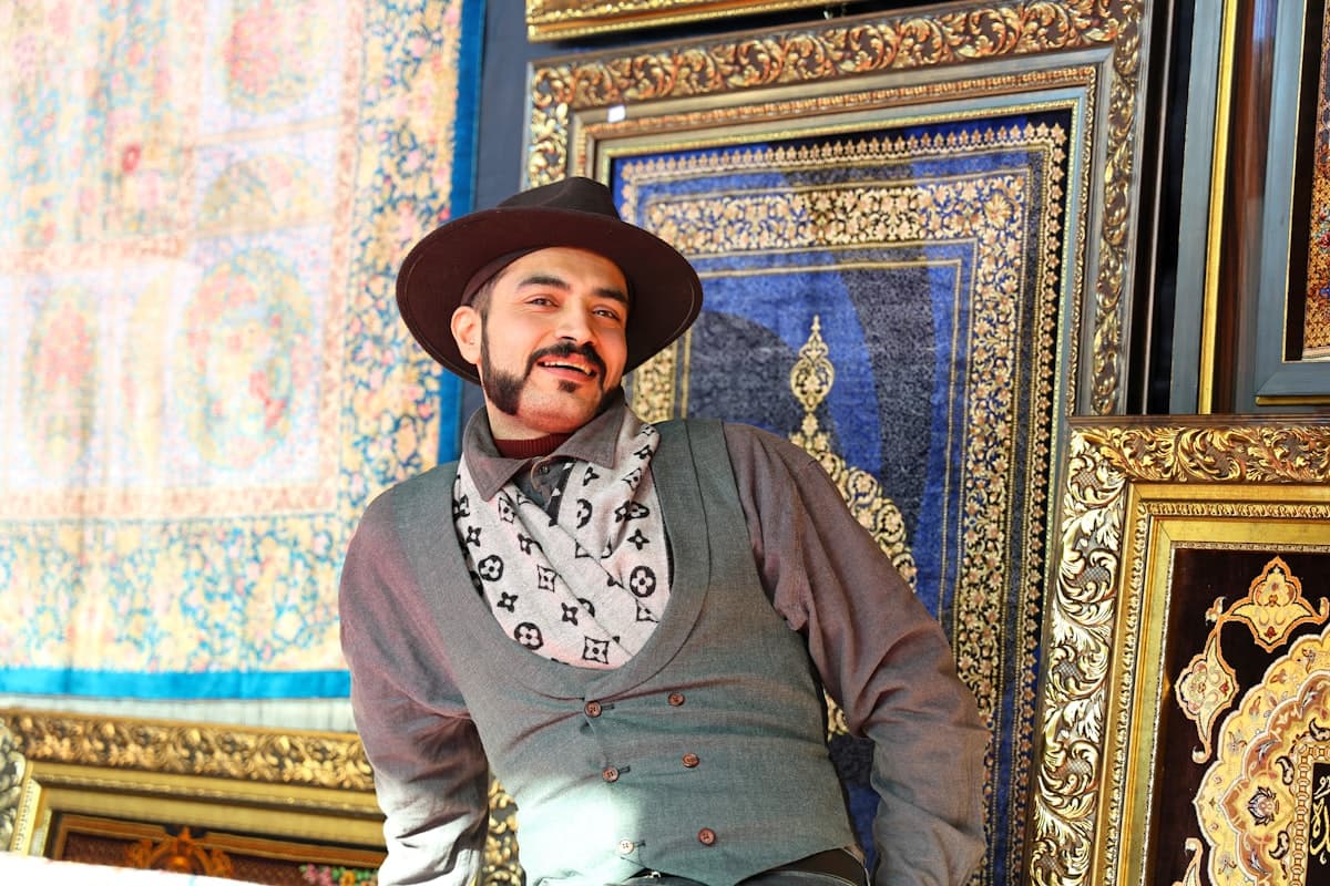 Man in hat and vest surrounded by carpets