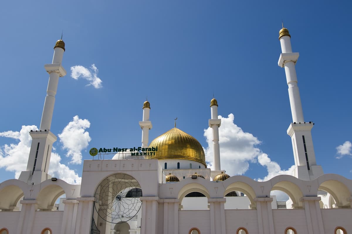 Golden domed mosque with white minarets under blue sky
