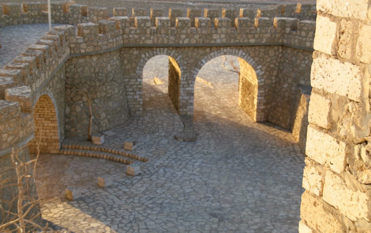 Stone courtyard with arched walkways and crenellated walls