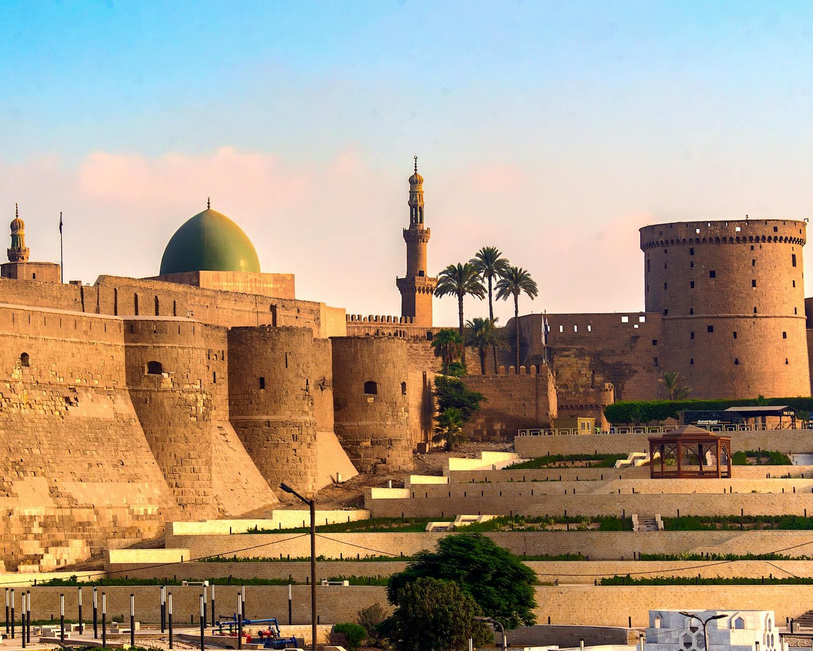 Ancient citadel with minarets and dome in a sunny cityscape setting, showcasing rich architecture.