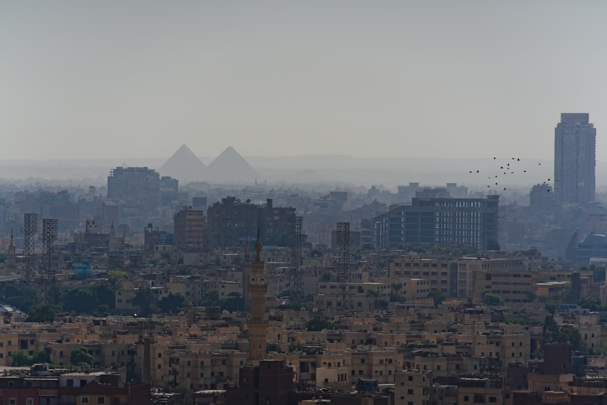 Pyramids visible over a hazy cityscape with modern buildings.
