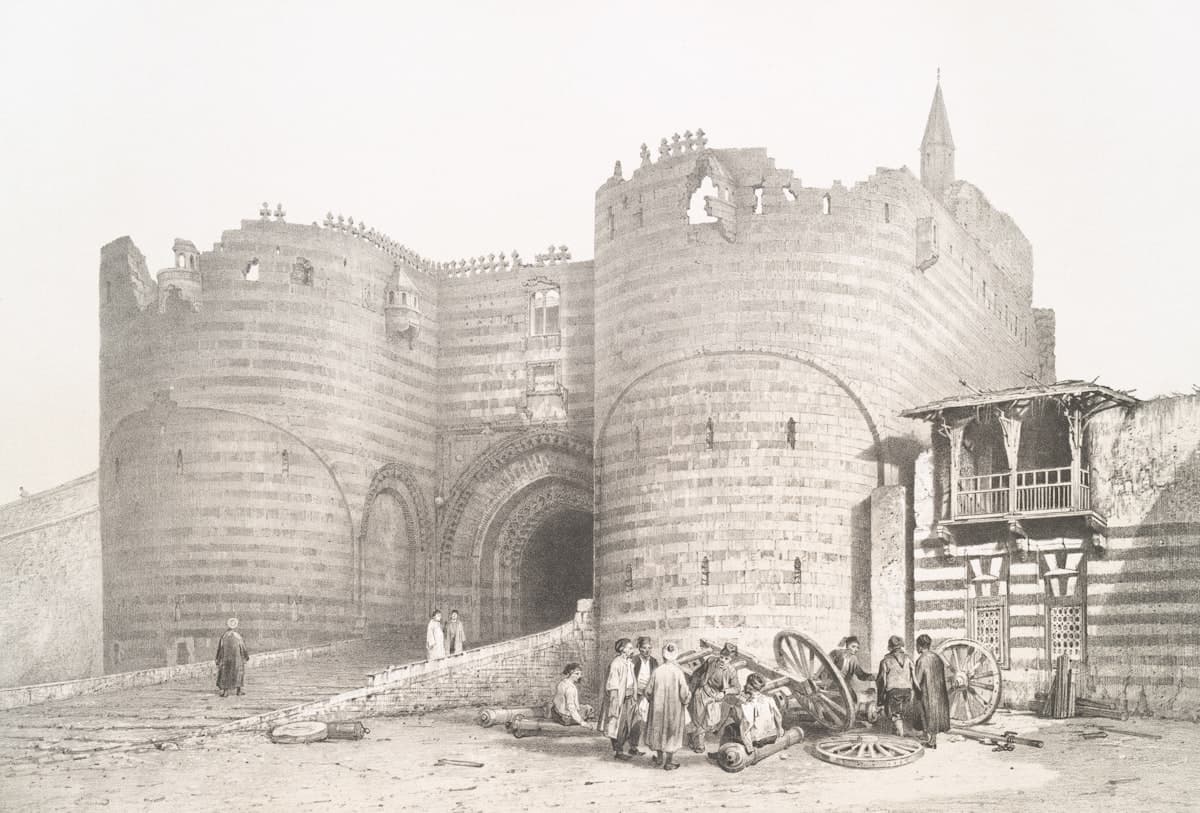 Ancient stone gate with people and cannons outside structures