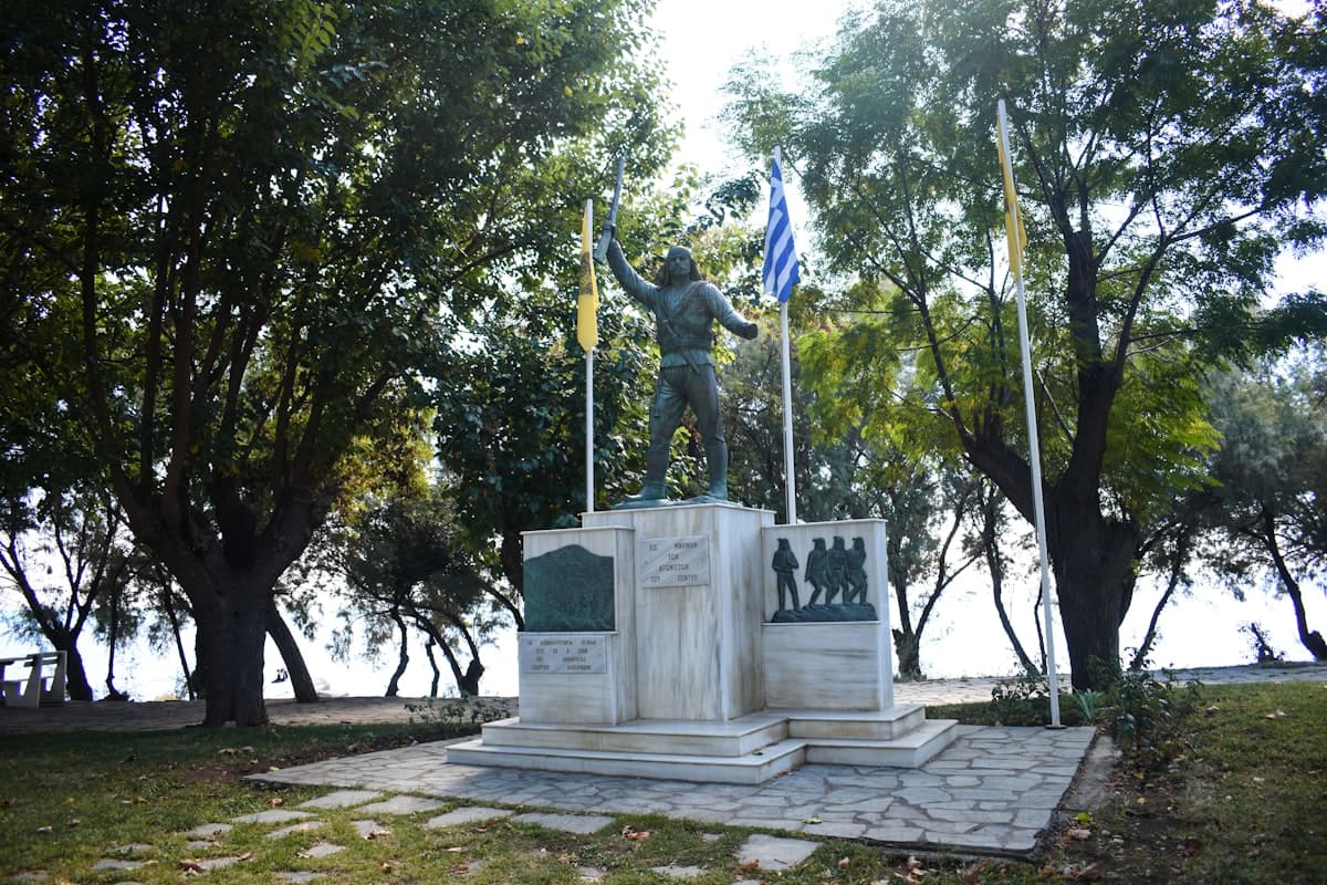 Monument with statue and flags in a park setting