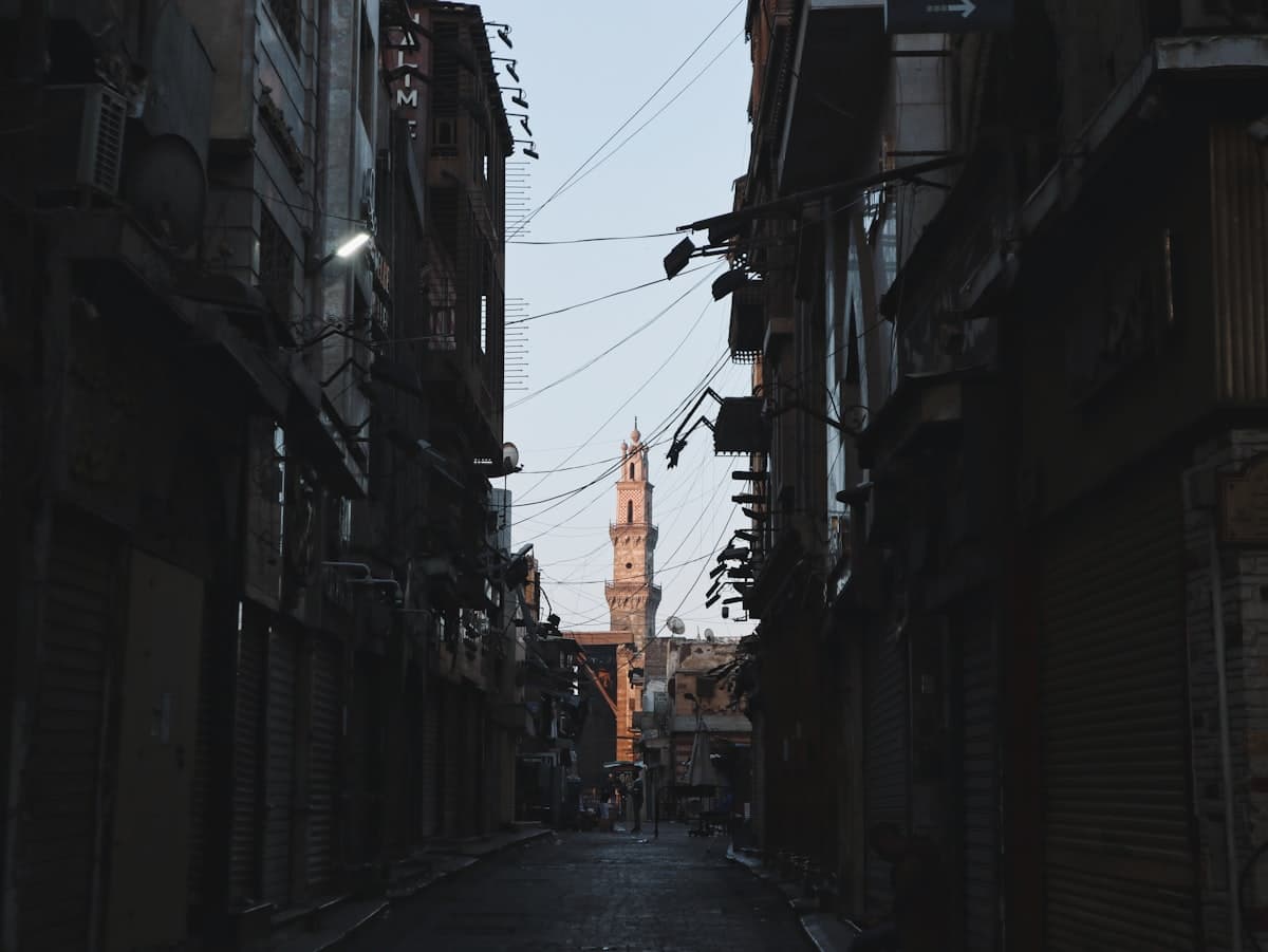 a narrow alley way with a clock tower in the background