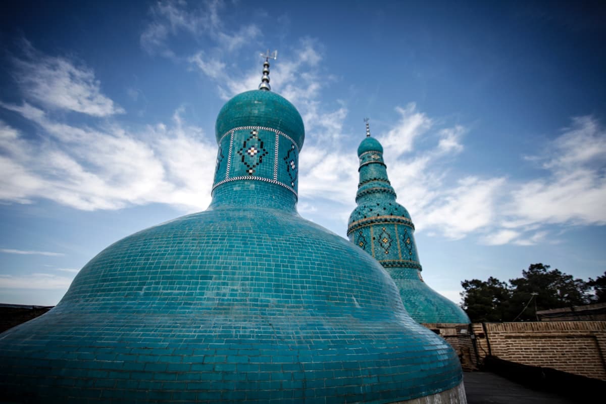 a large blue building with two towers and a sky background
