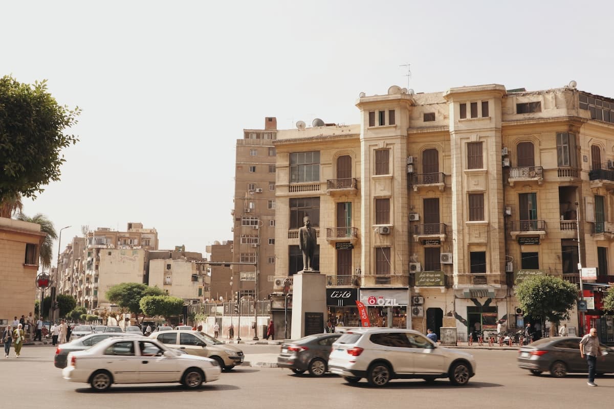 a group of cars driving down a street next to tall buildings