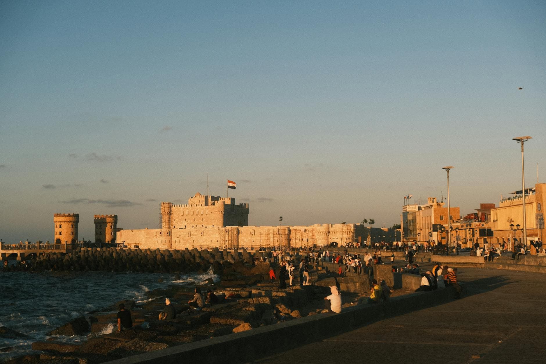 View of Fort Qaitbay in Alexandria, Egypt, with people enjoying an evening by the sea.