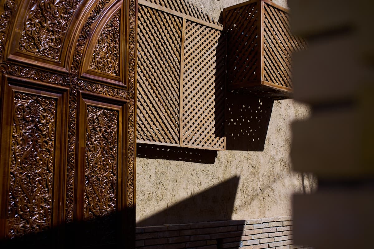 Intricately carved wooden doors and latticed windows cast shadows.