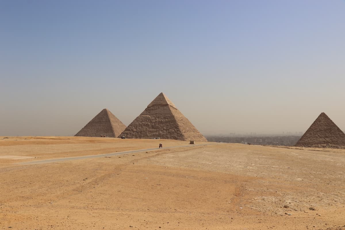 Three pyramids stand in a desert landscape.