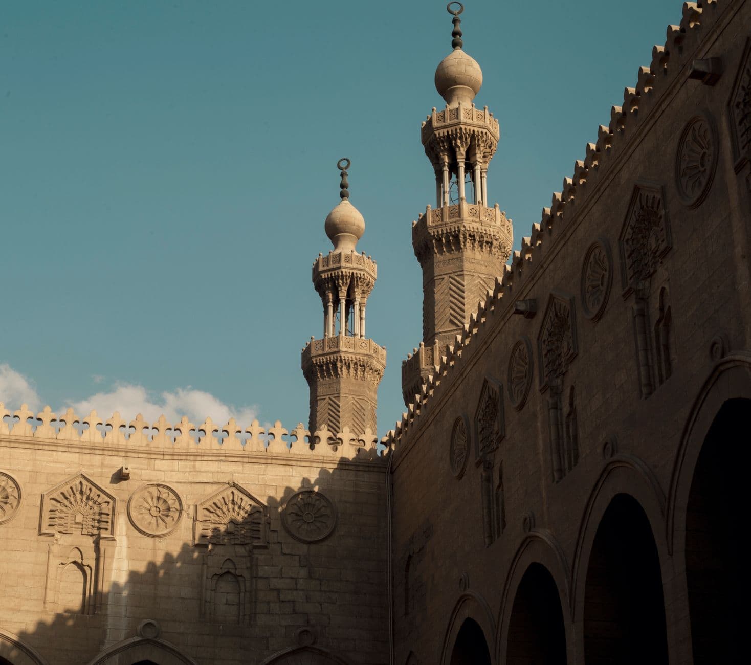 Ornate minarets of Sultan al-Muayyad Mosque against clear sky in Cairo, Egypt.