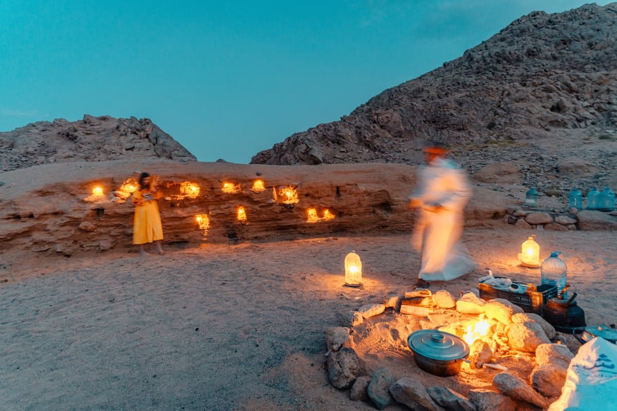 a group of people around a fire pit with a group of candles