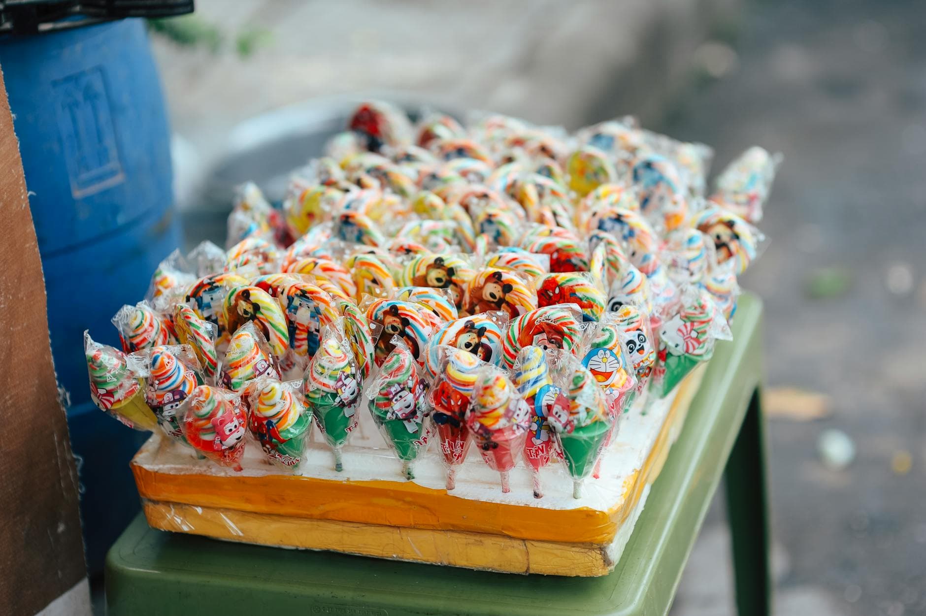 Vibrant assortment of wrapped lollipops arranged on a street market stand, showcasing bright colors and fun patterns.