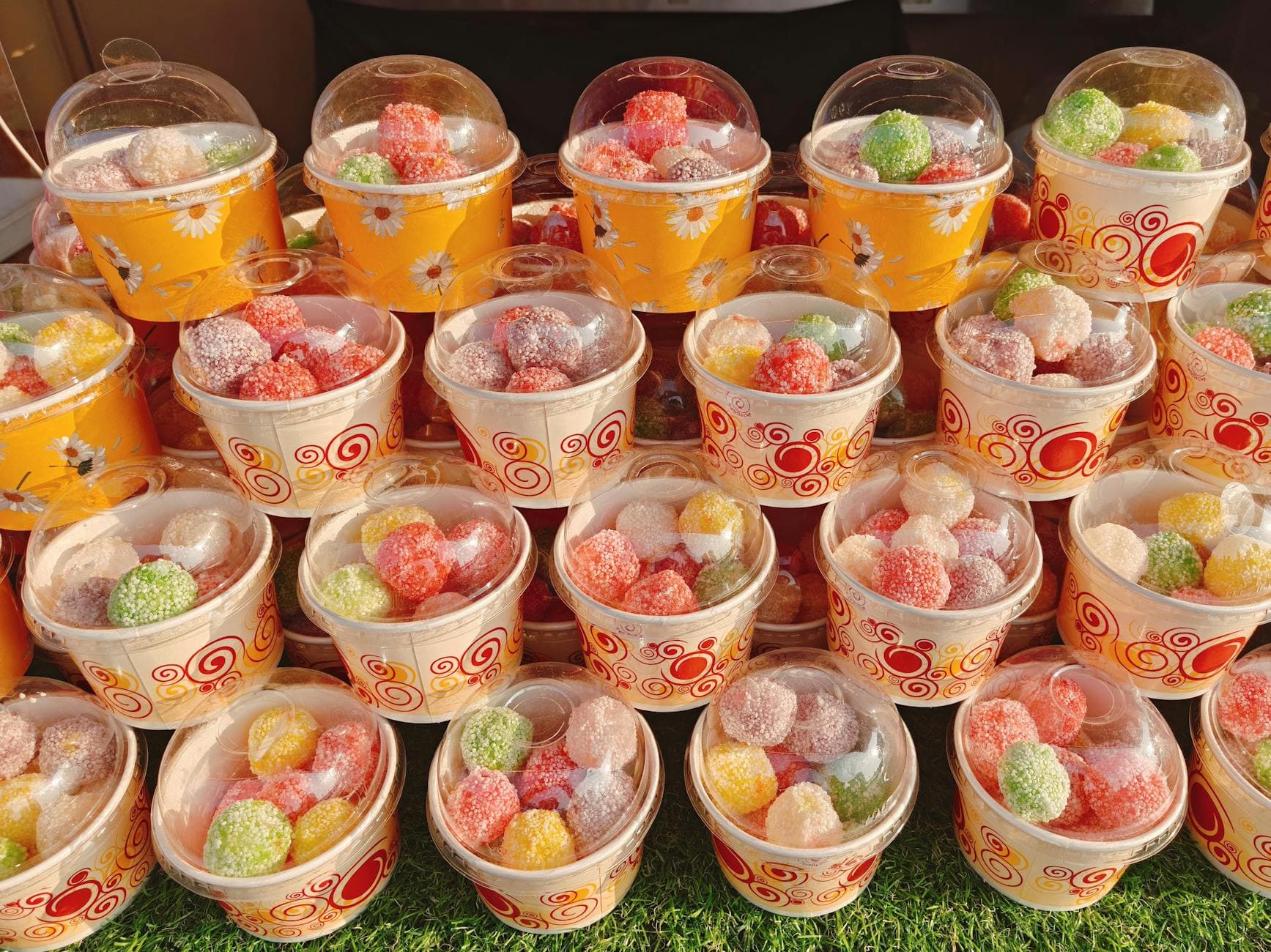 A vibrant array of sugar-coated jelly candies in decorative cups, displayed outdoors in Manila.