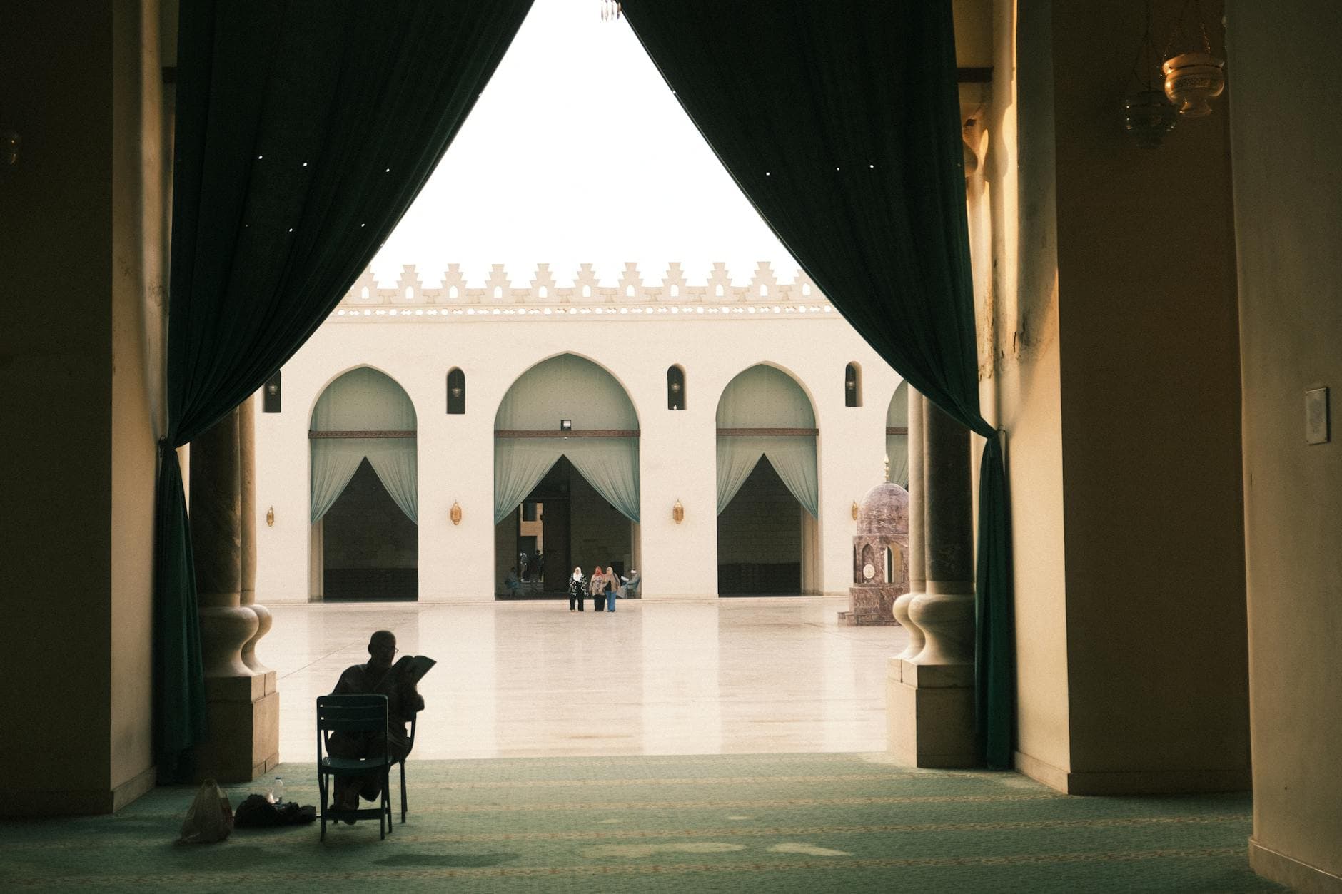 A peaceful view of a mosque courtyard in Cairo, Egypt, with a person seated inside.