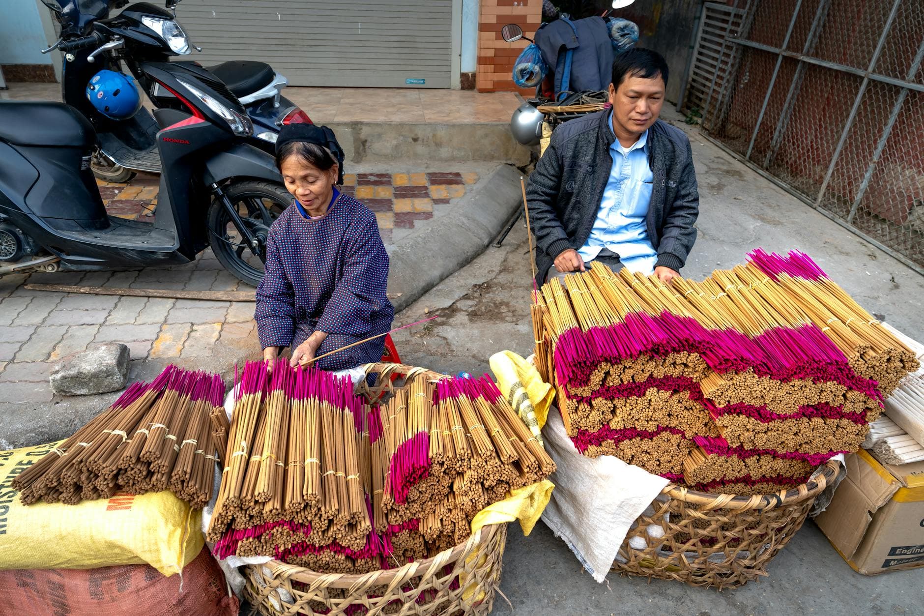 A man and woman sell incense sticks on a street. Vibrant colors and cultural expression.
