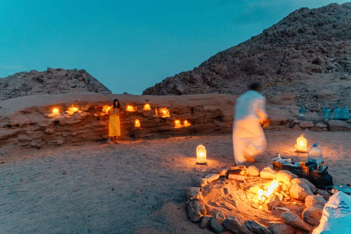 a man and woman standing next to a fire pit with a couple of candles in it
