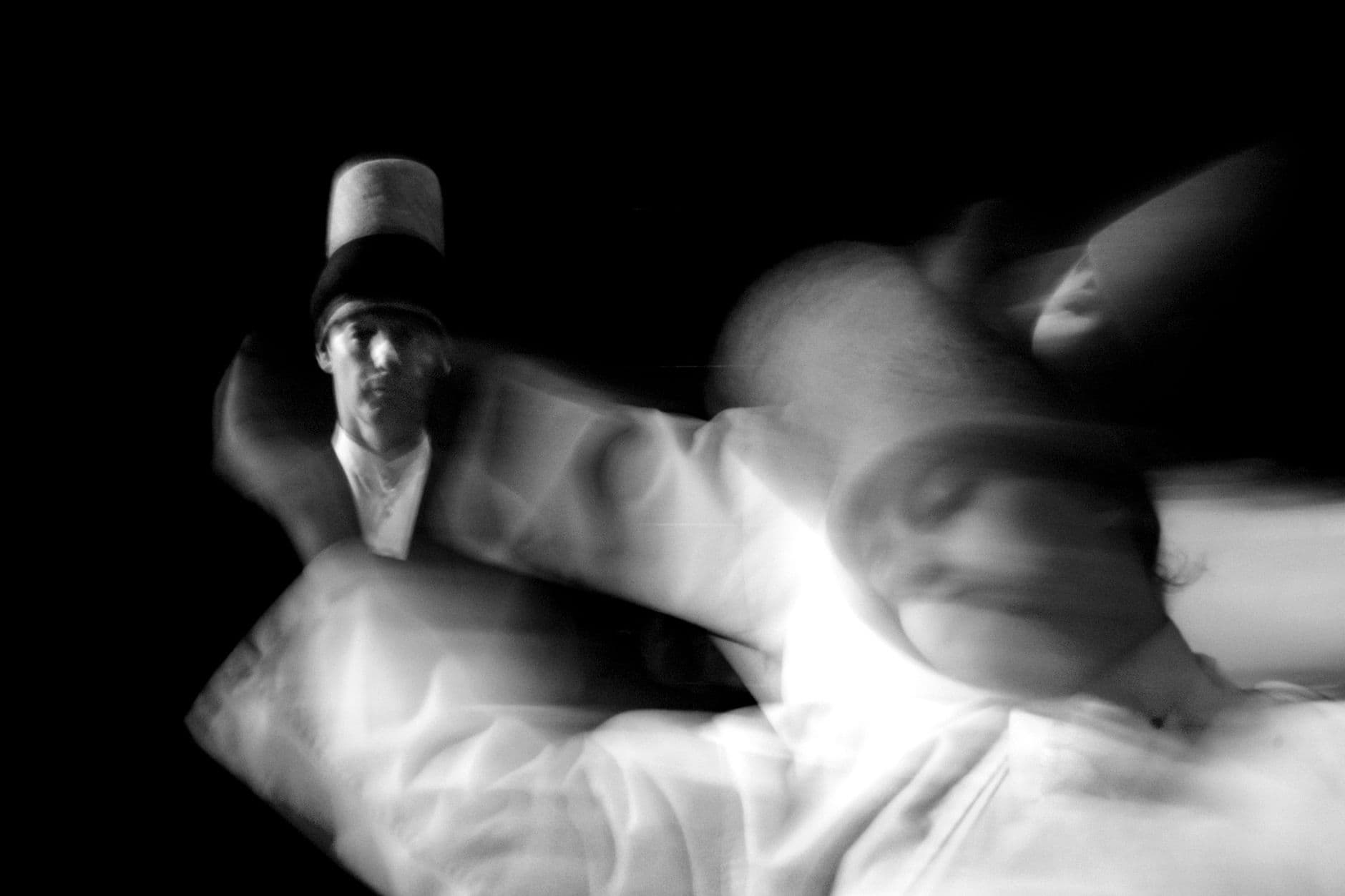 Blurred black and white shot of whirling dervish dancers in motion showcasing mystic performance art.