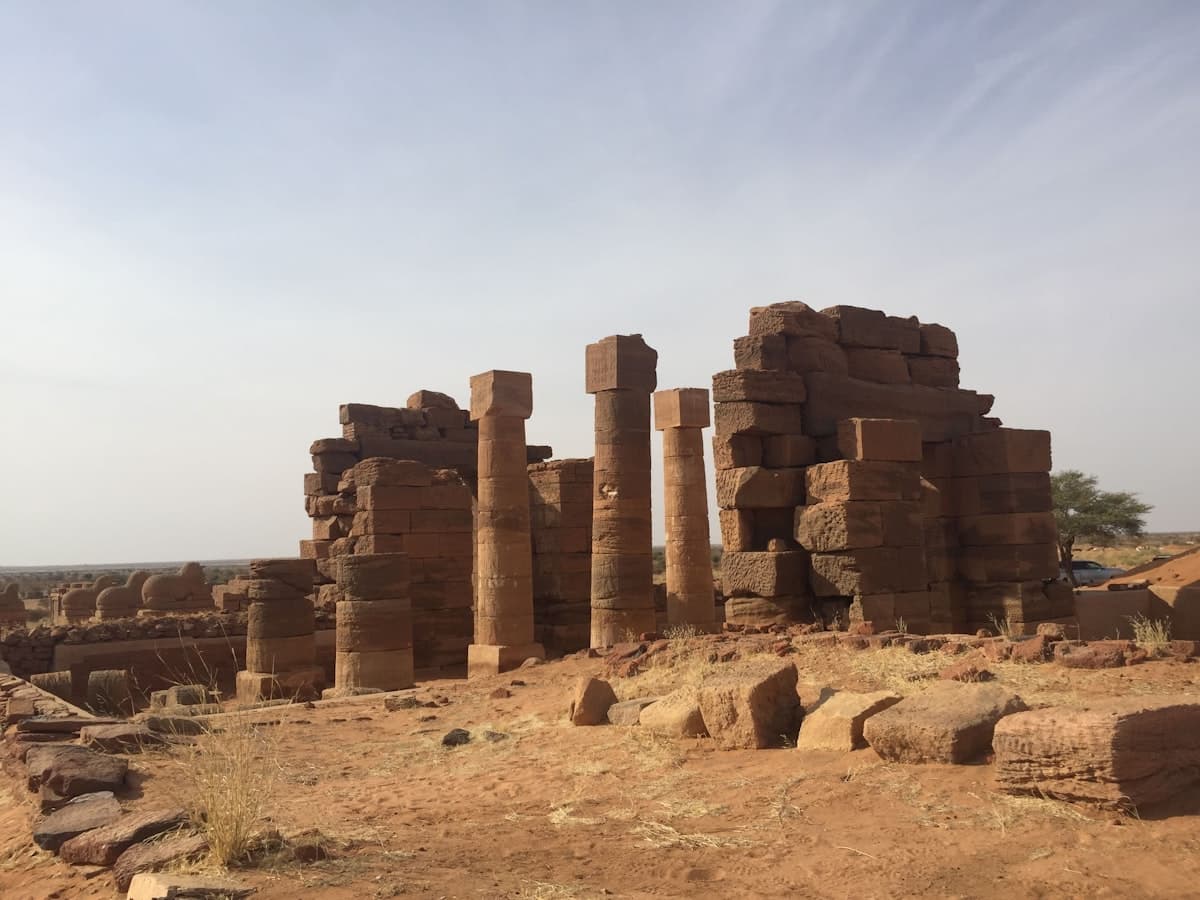 Ancient stone ruins with tall pillars under a clear sky.
