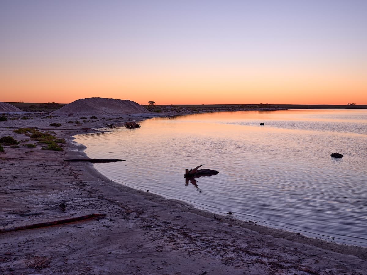 Calm lake at sunset with distant hills