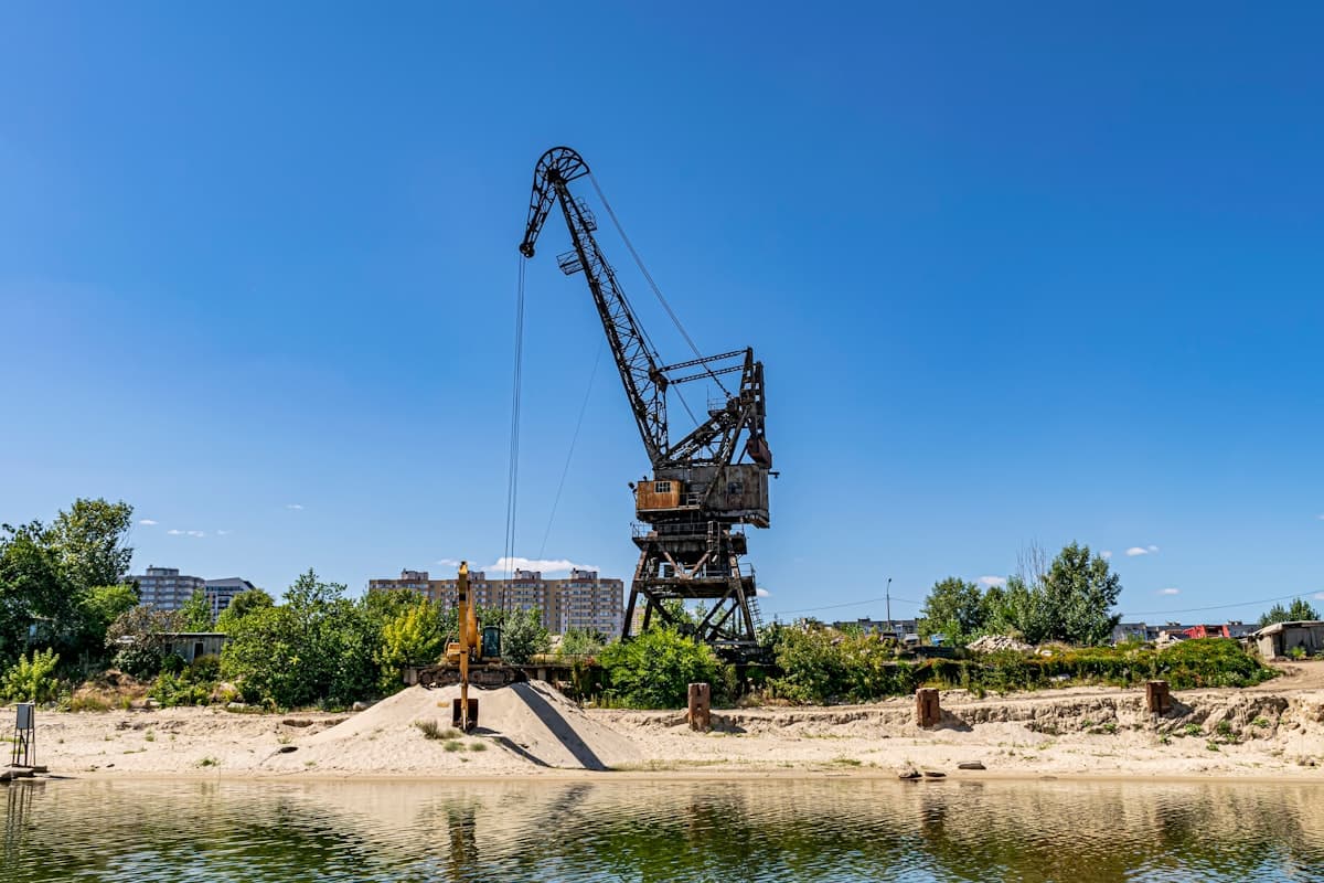 a crane sitting on top of a beach next to a body of water